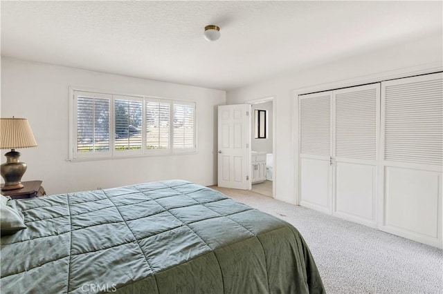 bedroom with light colored carpet, ensuite bathroom, and a closet
