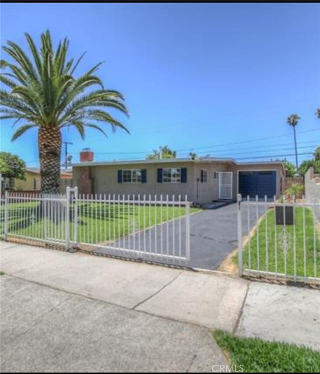 ranch-style house featuring a fenced front yard, a front lawn, aphalt driveway, a garage, and a gate
