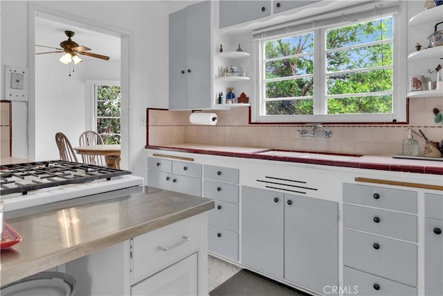kitchen featuring a ceiling fan, open shelves, decorative backsplash, and a sink