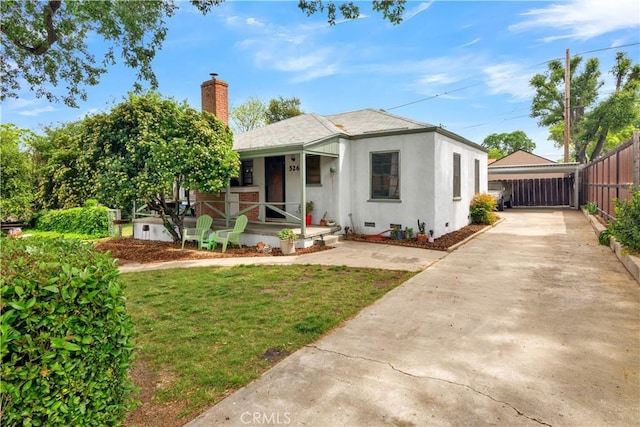 bungalow with fence, covered porch, a front yard, a chimney, and driveway