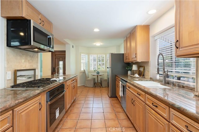 kitchen with decorative backsplash, a sink, light stone counters, stainless steel appliances, and light tile patterned flooring