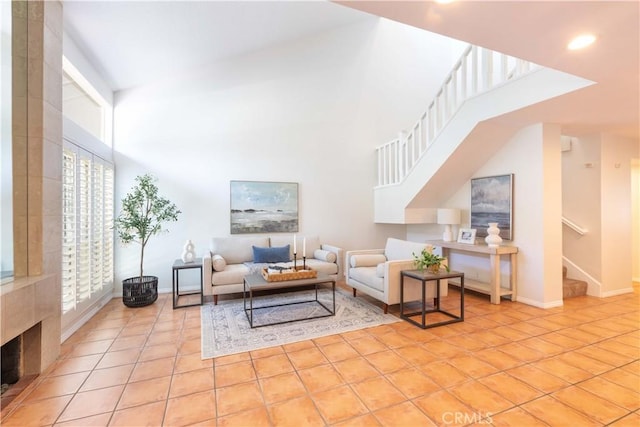 living area featuring stairway, tile patterned floors, baseboards, and a towering ceiling