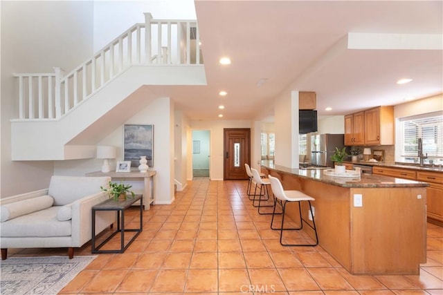 kitchen featuring a breakfast bar, open floor plan, recessed lighting, dark stone countertops, and appliances with stainless steel finishes