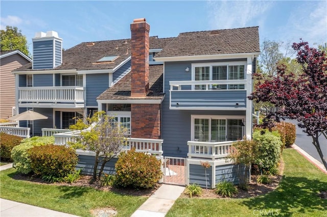 view of front of property featuring a gate, a chimney, and a balcony