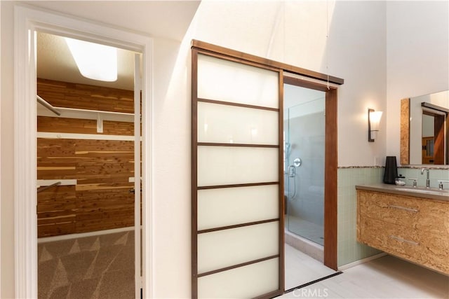 full bathroom featuring wood walls, a shower stall, and vanity
