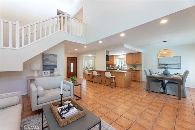 living area featuring stairs, recessed lighting, baseboards, and a towering ceiling