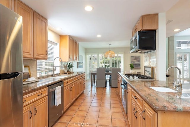 kitchen featuring backsplash, appliances with stainless steel finishes, a wealth of natural light, and a sink