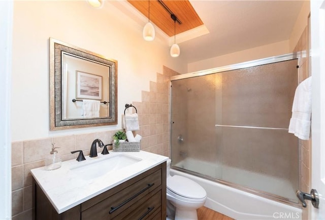 full bath with vanity, toilet, shower / bath combination with glass door, and tile walls