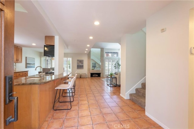kitchen with recessed lighting, a sink, open floor plan, and a kitchen bar