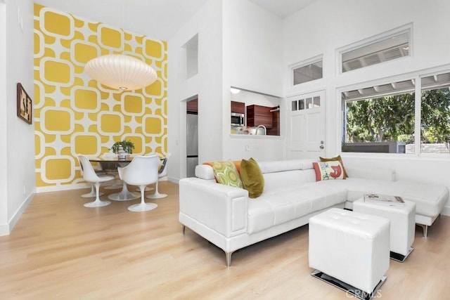 living room with baseboards, a towering ceiling, and wood finished floors