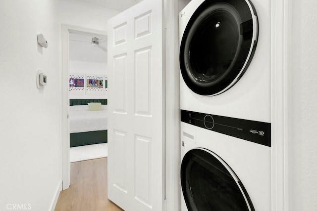 laundry room with light wood-style floors, laundry area, and stacked washer / dryer