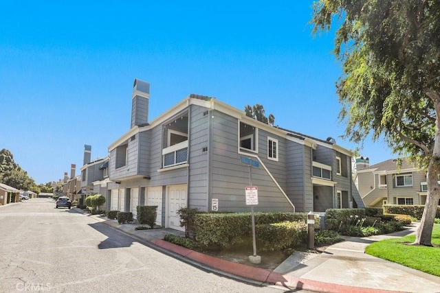 view of side of property featuring a garage, a chimney, and a residential view