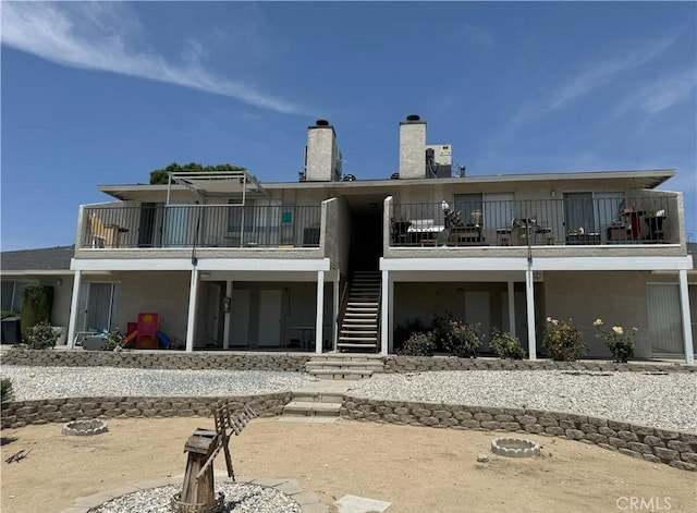 rear view of house with a chimney, a balcony, and stairs