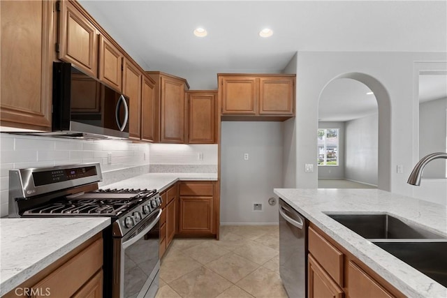 31937 Calle Galarza, Temecula, CA 92592 - kitchen with appliances with stainless steel finishes, a sink, brown cabinetry, recessed lighting, and tasteful backsplash