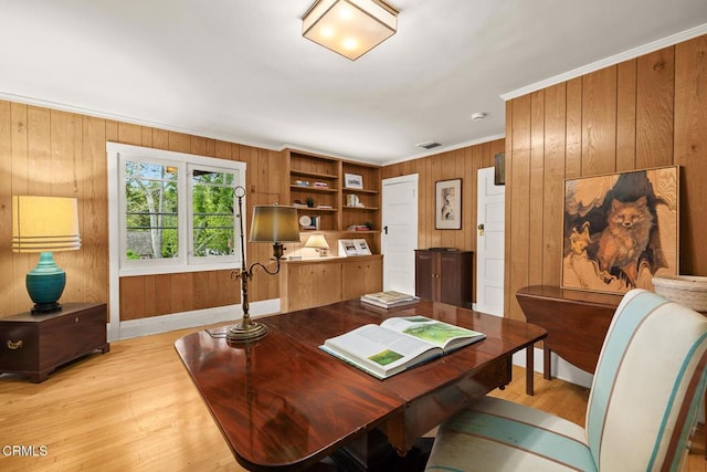 home office featuring crown molding, wood walls, visible vents, and light wood-style floors