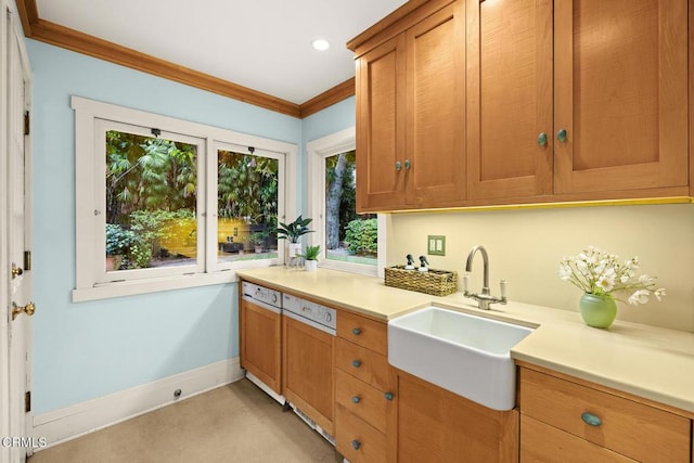 kitchen with ornamental molding, baseboards, light countertops, brown cabinets, and a sink