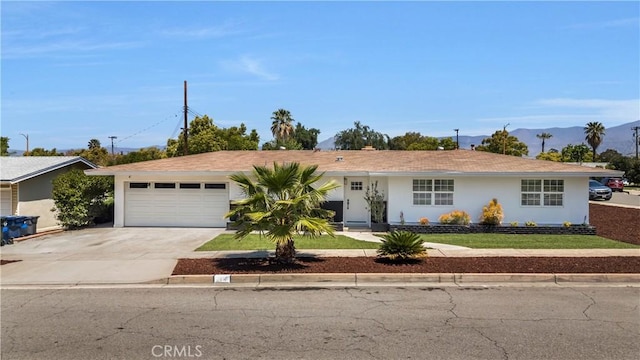 ranch-style house featuring driveway, a mountain view, a front lawn, an attached garage, and stucco siding