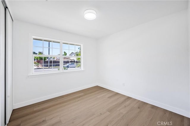 spare room featuring baseboards and wood finished floors