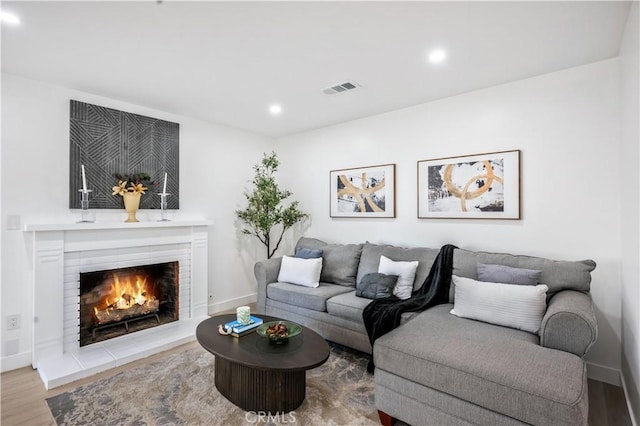 living room featuring visible vents, a fireplace, wood finished floors, baseboards, and recessed lighting
