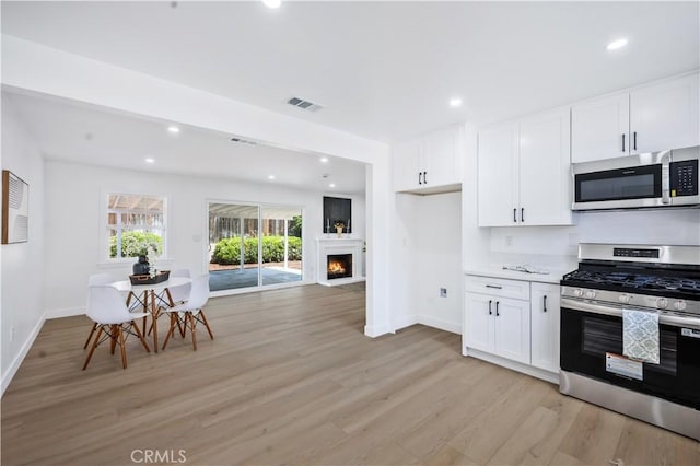 kitchen featuring visible vents, appliances with stainless steel finishes, baseboards, light wood-style floors, and white cabinetry