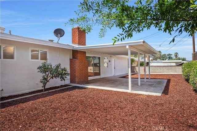 back of house featuring fence, a patio, a chimney, and stucco siding