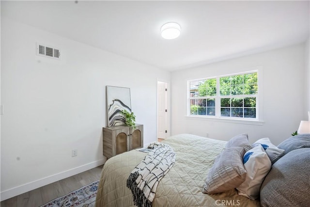 bedroom with baseboards, wood finished floors, and visible vents