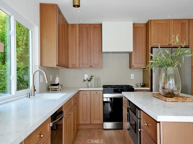 kitchen with a sink, a healthy amount of sunlight, light stone countertops, and stainless steel appliances