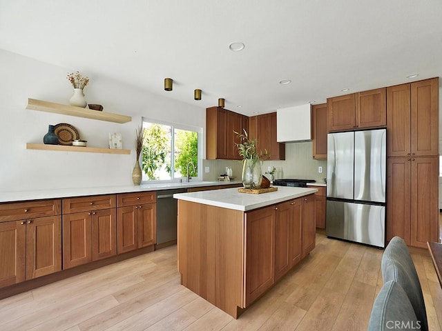 kitchen with appliances with stainless steel finishes, open shelves, light wood-type flooring, light countertops, and a sink