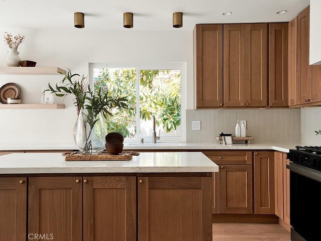 kitchen featuring open shelves, a sink, brown cabinets, and gas stove