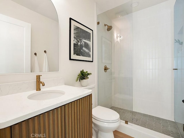 full bathroom with vanity, a tile shower, and toilet