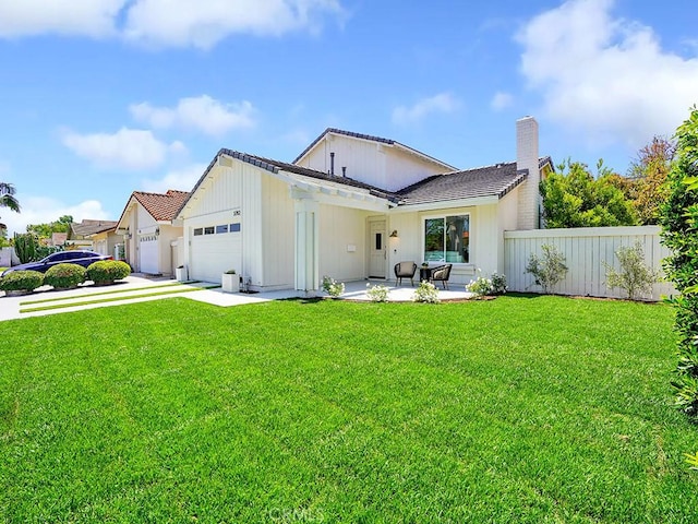rear view of property featuring a garage, fence, a yard, a chimney, and driveway