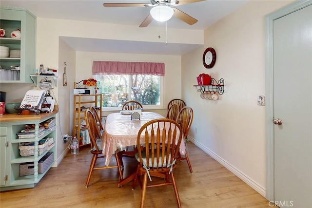 dining room featuring baseboards, a ceiling fan, and light wood-style flooring