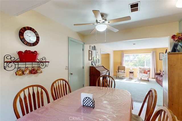 carpeted dining space featuring ceiling fan and visible vents