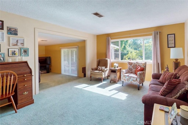 carpeted living room featuring a textured ceiling and visible vents