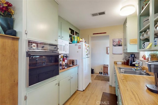 kitchen with open shelves, a sink, light wood-style floors, white appliances, and visible vents