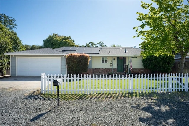 single story home featuring a garage, a fenced front yard, solar panels, and driveway