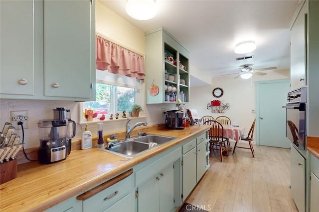 kitchen featuring a ceiling fan, visible vents, a sink, light countertops, and oven