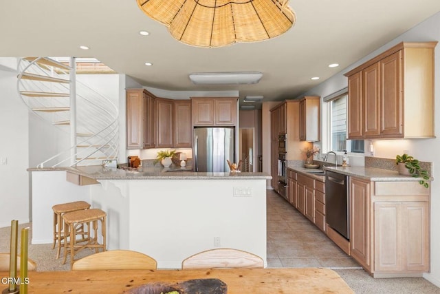 kitchen featuring appliances with stainless steel finishes, light stone counters, a kitchen breakfast bar, a peninsula, and recessed lighting