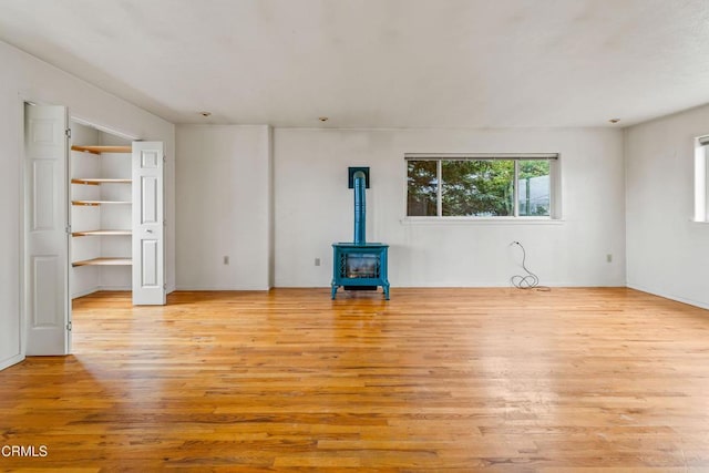 unfurnished living room with light wood finished floors and a wood stove