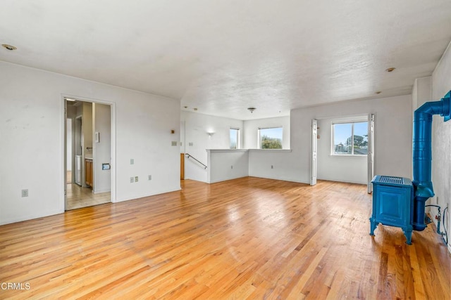 unfurnished living room with a wood stove and light wood-style floors