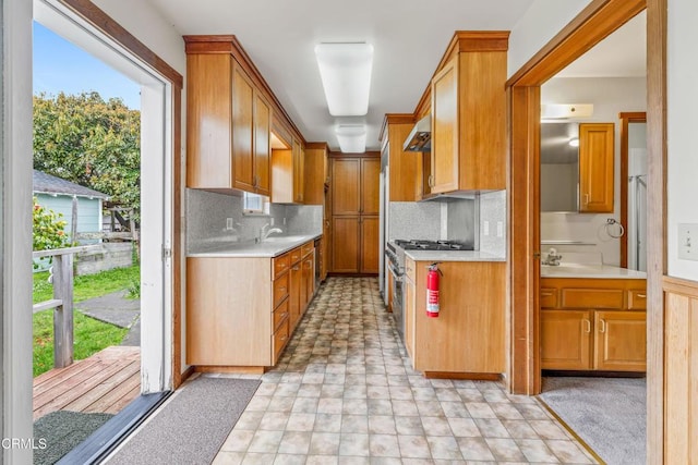 kitchen with light countertops, high end stove, decorative backsplash, and under cabinet range hood