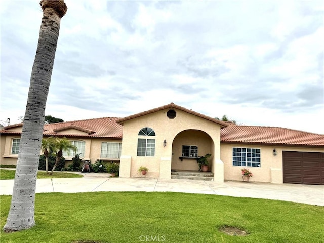 2285 W 2nd Ave, San Bernardino, CA 92407 - mediterranean / spanish house featuring stucco siding, a tile roof, a front yard, a garage, and driveway