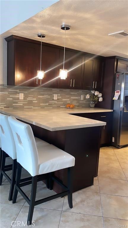 2285 W 2nd Ave, San Bernardino, CA 92407 - bar with stainless steel refrigerator with ice dispenser, backsplash, light tile patterned floors, and decorative light fixtures