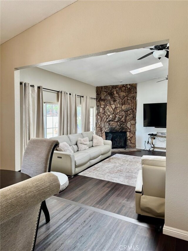 2285 W 2nd Ave, San Bernardino, CA 92407 - living area with wood finished floors, a stone fireplace, a ceiling fan, baseboards, and a skylight