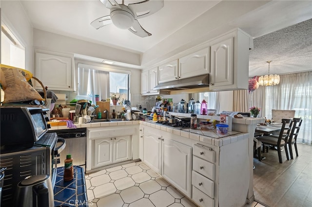 10139 Hayvenhurst Ave, North Hills, CA 91343 - kitchen featuring tile counters, under cabinet range hood, ceiling fan, a peninsula, and a sink