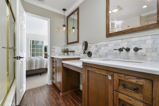 ensuite bathroom with enclosed tub / shower combo, tasteful backsplash, wood finished floors, vanity, and ornamental molding