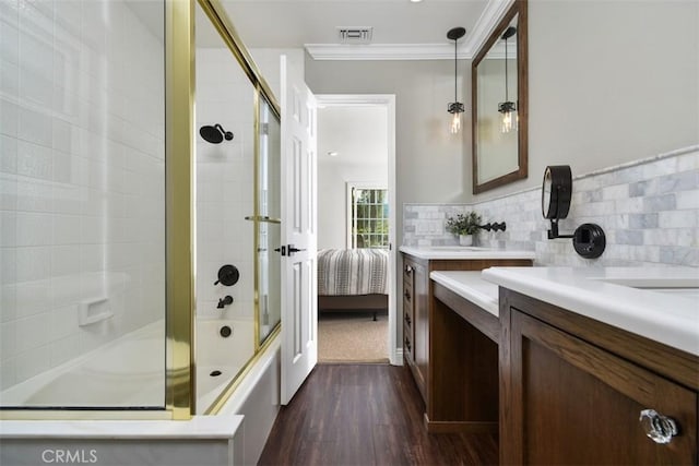 ensuite bathroom with visible vents, crown molding, vanity, wood finished floors, and combined bath / shower with glass door