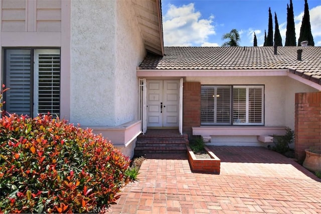 doorway to property with stucco siding and a tiled roof
