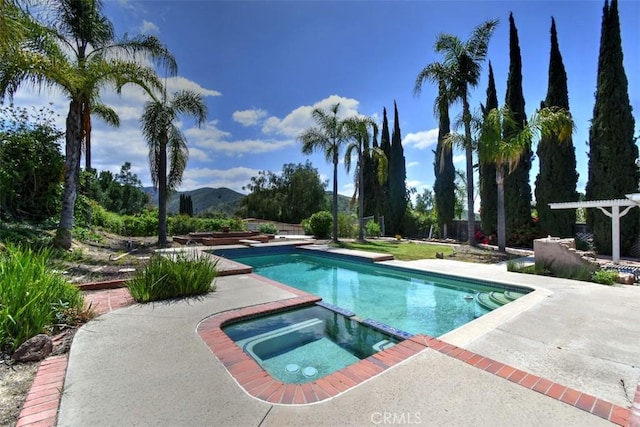 view of pool featuring a patio, a pool with connected hot tub, and a mountain view
