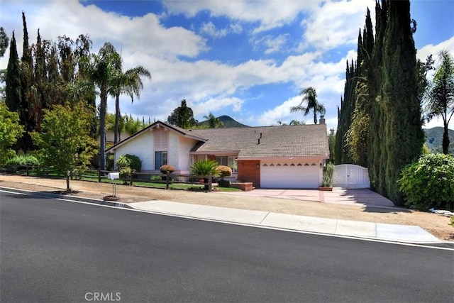 view of front facade featuring fence, a garage, stucco siding, a gate, and driveway